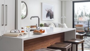 A modern kitchen with white cabinets, a central island with stools, and pendant lighting.