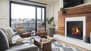 A modern living room with a fireplace, large windows, and a cozy seating area.