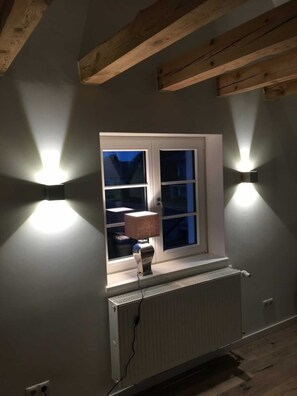 A room with a window, a radiator, and two wall-mounted lights. - Apartment B OG (on 2 floors) - Christmann's Cottage Apartment An on the ground floor and (Weisenheim am Berg)