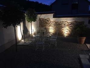 An outdoor patio with a stone wall, metal chairs, and a table. - Apartment B OG (on 2 floors) - Christmann's Cottage Apartment An on the ground floor and (Weisenheim am Berg)