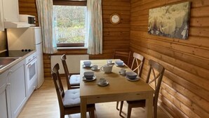 Uma cabana de madeira com cozinha, área de jantar e janela com cortinas.