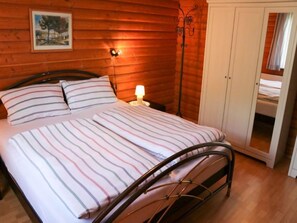 A wooden-paneled bedroom with a bed, a nightstand, and a wardrobe.