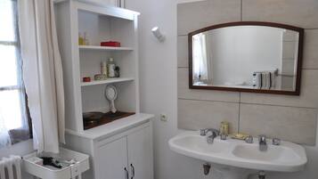 A bathroom with a white vanity, a sink, and a mirror.
