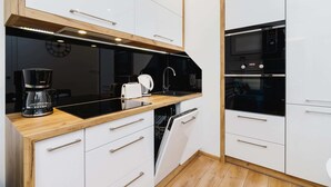 Eine moderne Küche mit weißen Schränken, einer schwarzen Arbeitsplatte, einer Kaffeemaschine, einem Toaster und einem Geschirrspüler.