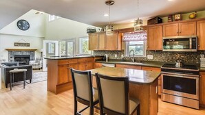 Una cocina moderna con armarios de madera, electrodomésticos de acero inoxidable e iluminación colgante.