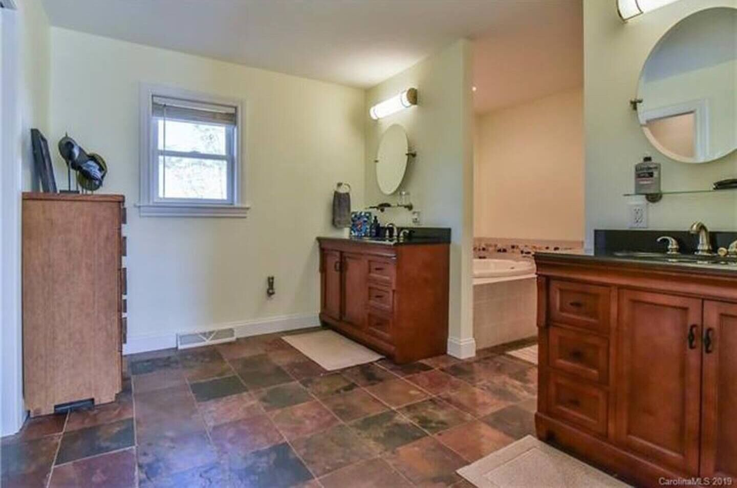 A bathroom with a large vanity, a bathtub, and a window.