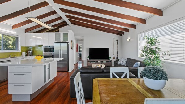 A modern kitchen with white cabinets, a central island, and a dining area with a wooden table and chairs.