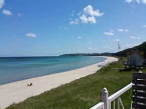 Une plage avec une tour de surveillance pour les sauveteurs, un ciel bleu dégagé et une mer calme.