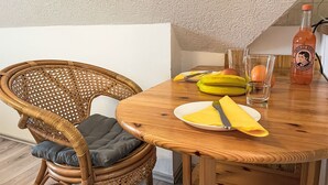 Ein Essbereich mit einem Holztisch, einem Korbstuhl und einer Flasche Thomas Henry Grapefruitsaft.