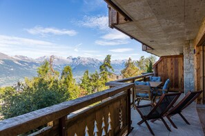 A wooden balcony with a view of mountains, a stone wall, and outdoor furniture. - Nendaz 2 bedroom apartment - close ski lift (R31) (Haute-Nendaz)
