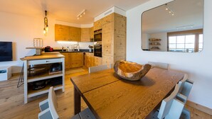 Eine moderne Küche mit Holzausstattung, einem Esstisch mit einer außergewöhnlichen Dekoration und einem großen Spiegel an der Wand.