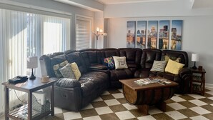 Una sala de estar con un sofá modular, una mesa de centro de madera y un suelo a cuadros.