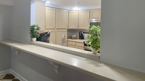 Una cocina moderna con armarios de colores claros, una campana extractora de acero inoxidable y dos plantas en macetas sobre la encimera.