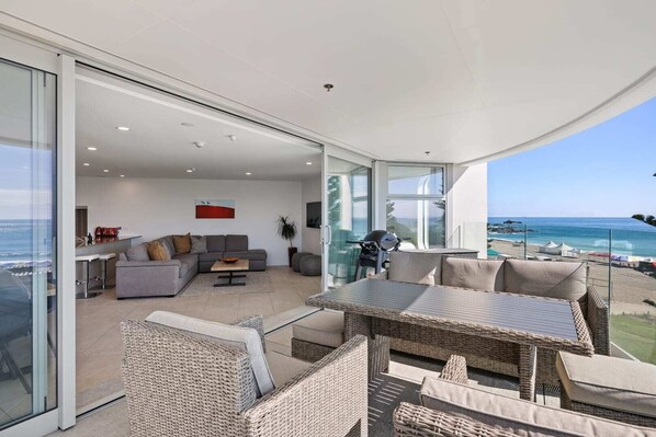 A modern living room with a glass sliding door leading to a balcony overlooking the sea.