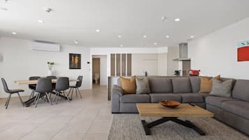 Un salon moderne avec un canapé gris, une table basse en bois et un coin repas comprenant une table et des chaises.