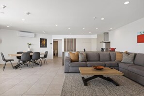 Una sala de estar moderna con un sofá gris, una mesa de centro de madera y un comedor con mesa y sillas.
