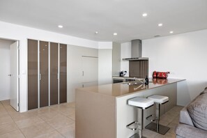 A modern kitchen with a central island, bar stools, and a built-in oven.