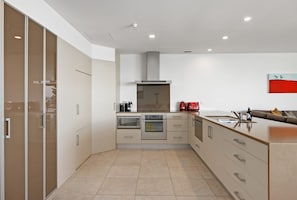 Una cocina moderna con electrodomésticos integrados, una isla grande y un armario con puerta corredera.