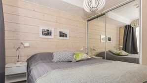 Ein Schlafzimmer mit einem großen Bett, zwei Nachttischen inklusive Lampen, einem Spiegel und gerahmten Bildern an der Wand.