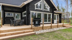 Eine Holzhütte mit Terrasse, Sitzgelegenheit im Freien und Grill.