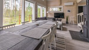 Ein großzügiger Wohnbereich mit einem großen Esstisch aus Holz, bequemen Sitzgelegenheiten, einem Fernseher und einem Kamin.