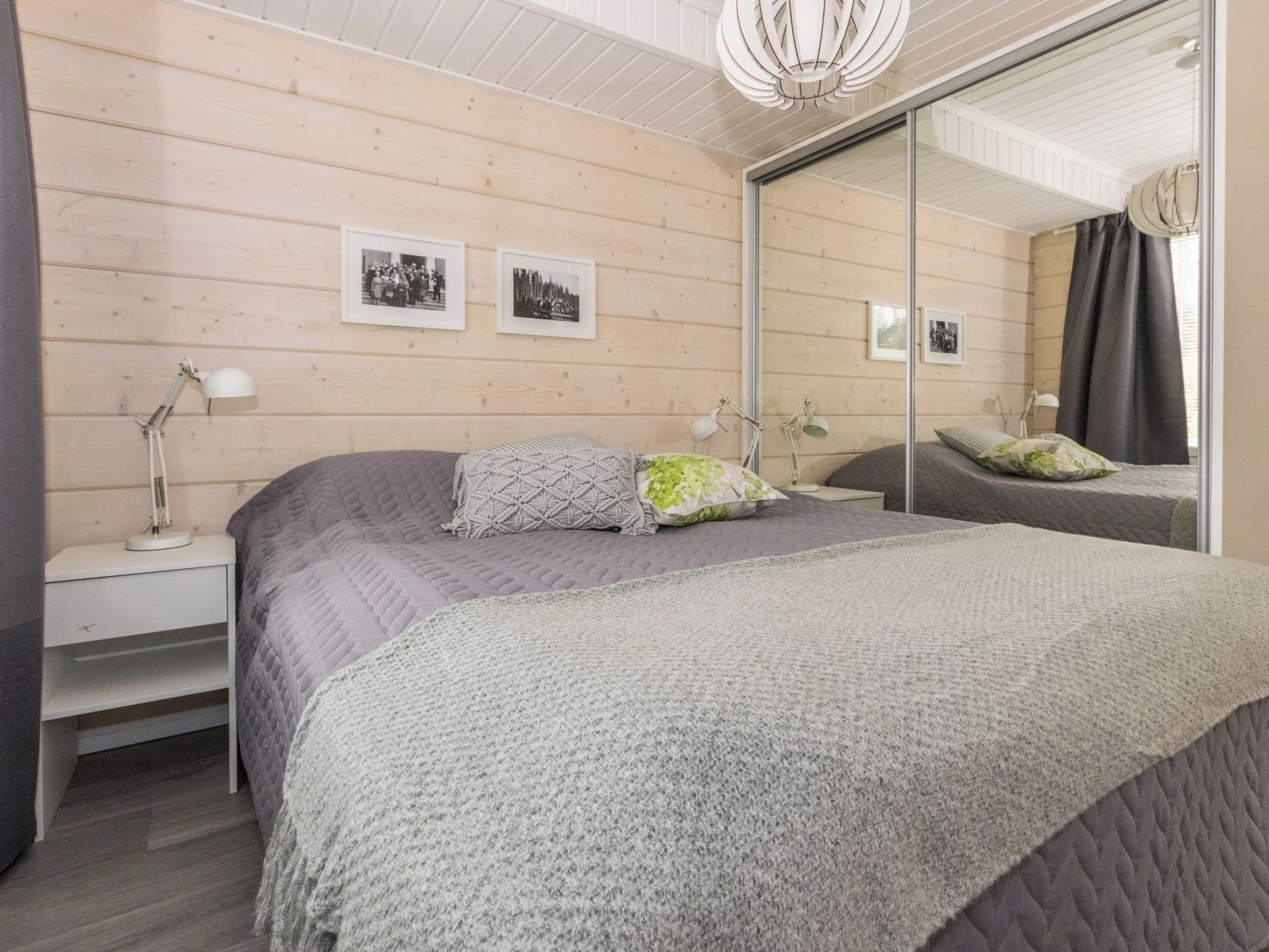 Un dormitorio con una cama grande, dos mesitas de noche con lámparas, un espejo y cuadros en la pared.