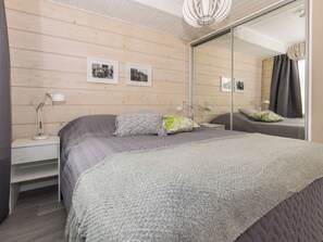 A bedroom with a large bed, two bedside tables with lamps, a mirror, and framed pictures on the wall.