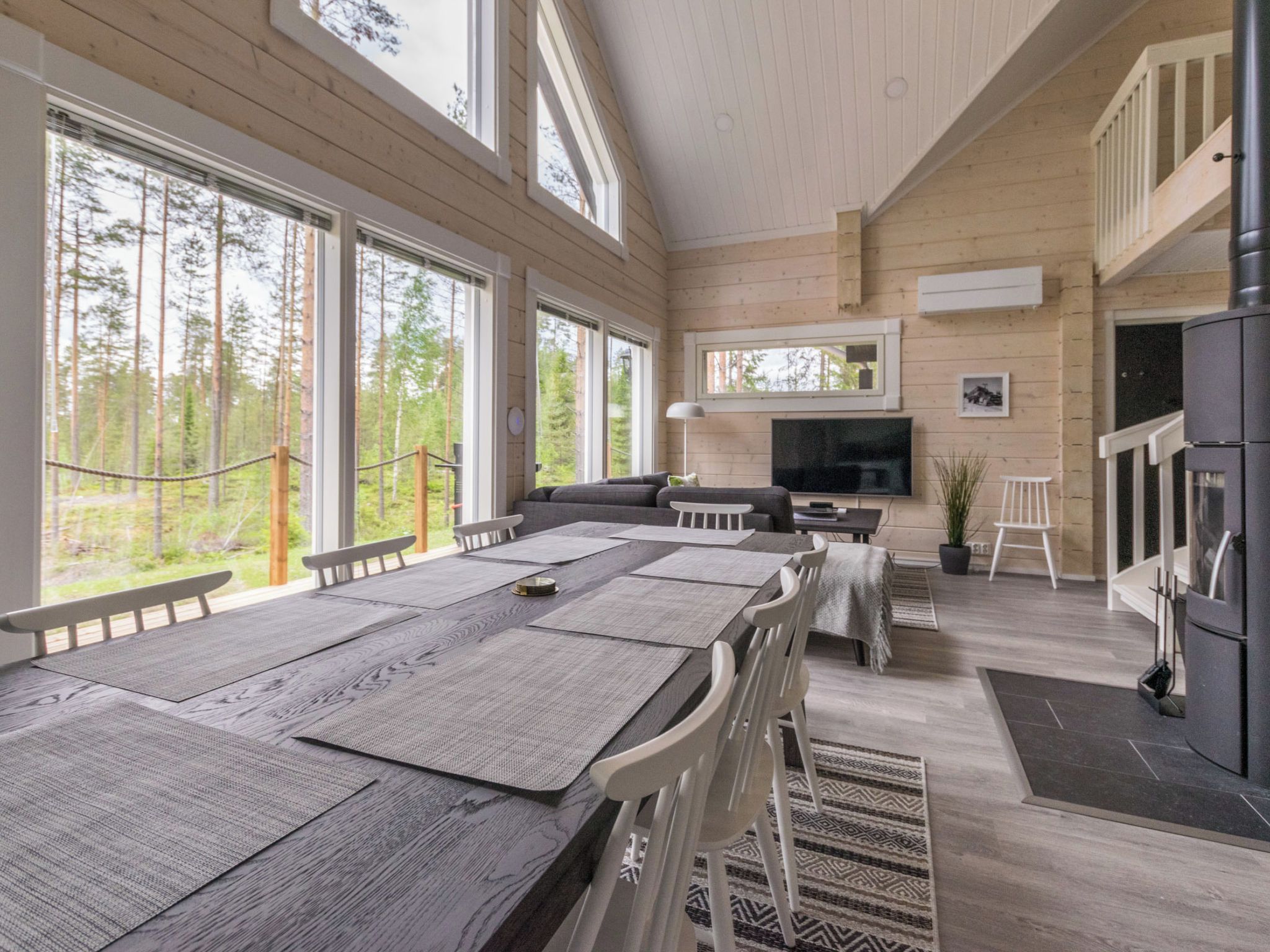 A spacious room with a large wooden dining table, a sofa, and a television.