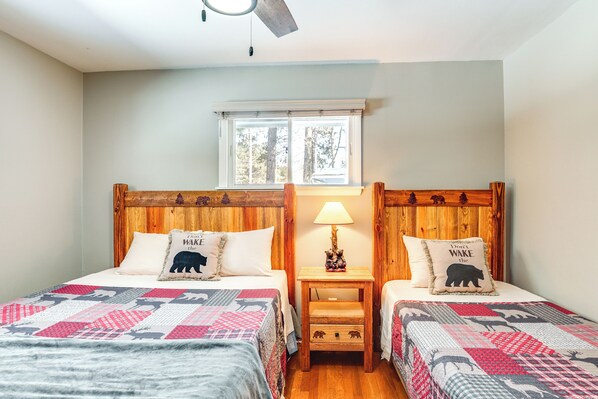 A bedroom with two beds, each with a wooden headboard, a window above, and a nightstand with a lamp between the beds. - Eagle River Lakefront Oasis w/ Private Dock! (Eagle River)