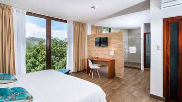 Habitación de hotel con una cama grande, un escritorio, un televisor y vistas a zonas verdes.