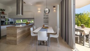 A modern kitchen with a central island, white chairs, and a dining table. - Beautiful villa with private pool, 3 bedrooms, 3 bathrooms, near the seaside! (Fazana)