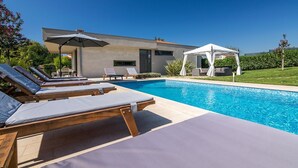 A modern pool area with lounge chairs and a gazebo. - Beautiful villa with private pool, 3 bedrooms, 3 bathrooms, near the seaside! (Fazana)