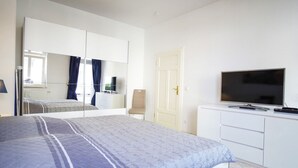 Une chambre à coucher avec un lit, une télévision, une commode et une armoire.