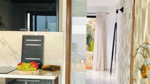 A modern kitchen with a marble countertop, a fruit bowl, and a wooden cabinet. - Canaryislandshost l Nazaret Suites (Nazaret)