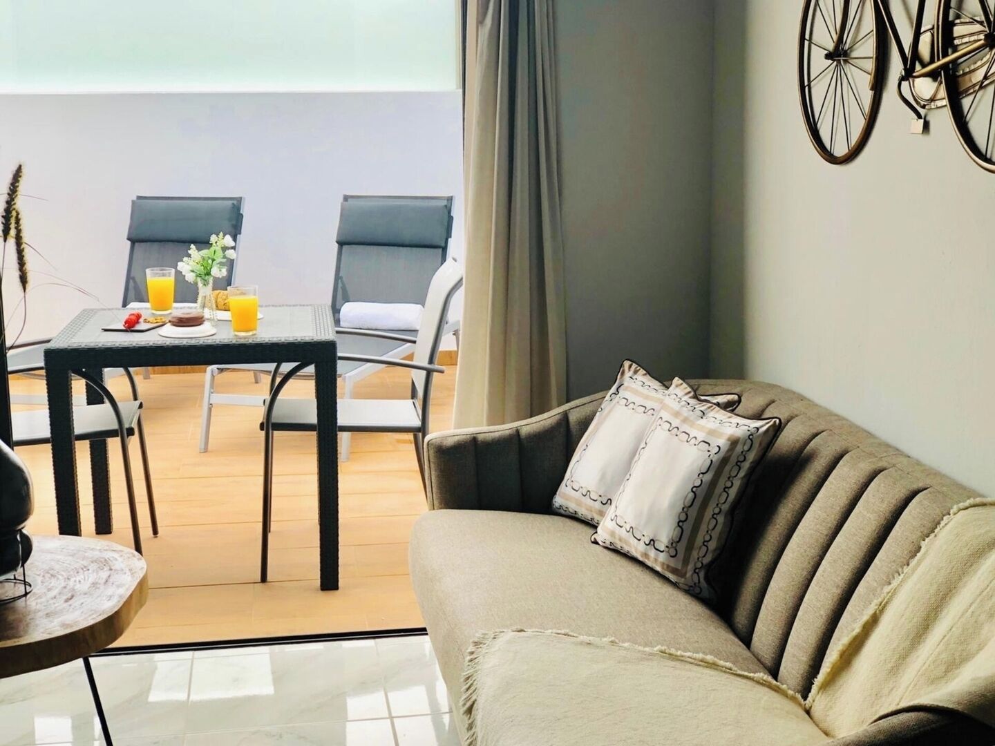 Een gezellige zithoek met een bank, een eettafel met stoelen, en een fiets aan de muur.