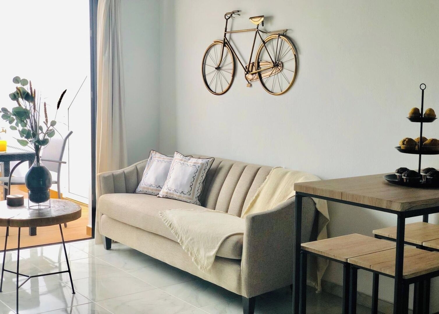 Un saló amb un sofà, una taula de dinar i una bicicleta penjada a la paret.
