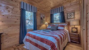 A wooden cabin bedroom with a bed, two bedside tables, a lamp, and a clock on the wall. - A Beary Nice View- Pet Friendly | Screened Porch | My Mountain | No steps to enter (Morganton)