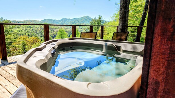 Un jacuzzi en una terraza de madera con una vista panorámica de las montañas.