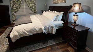 A bedroom with a bed, a nightstand, a lamp, a window with curtains, and a painting on the wall. - Raven Fox Farm-Country Charm! 5 BR Only 8 miles from Keeneland and BG Airport (Versailles)
