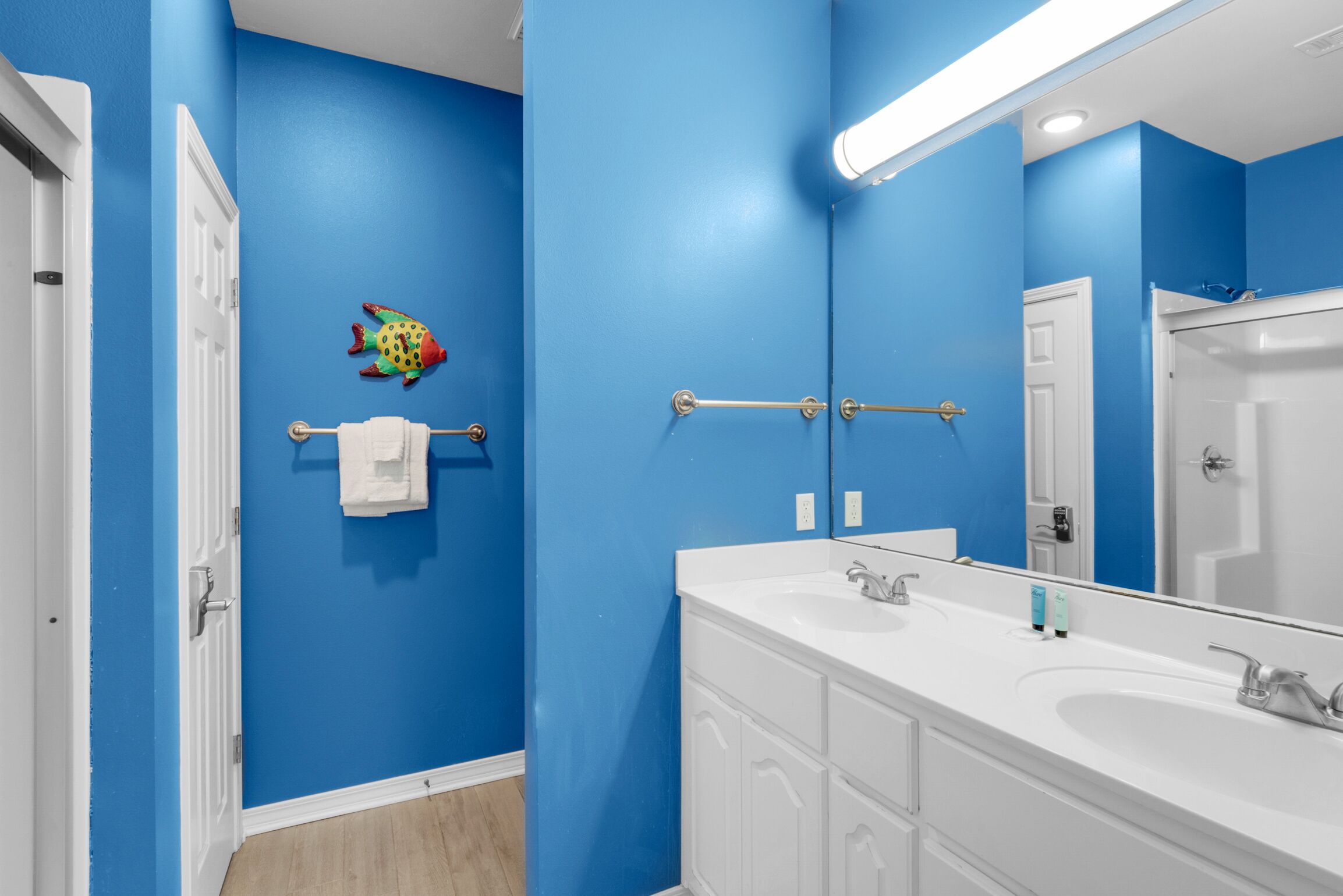 A bathroom with blue walls, white cabinets, a white sink, and a towel rack.