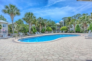 A swimming pool with lounge chairs and palm trees.