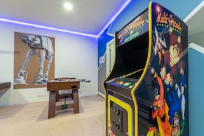 A room with a foosball table, a Star Wars-themed wall, and a Multi Arcade video game machine.