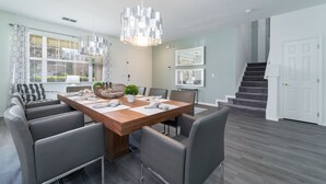 Un coin repas avec une table en bois, des chaises à revêtement gris et un lustre moderne.