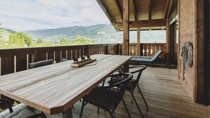 A wooden deck with a table and chairs, overlooking a mountainous landscape. - First IN Mountain Chalet A (Kaprun)