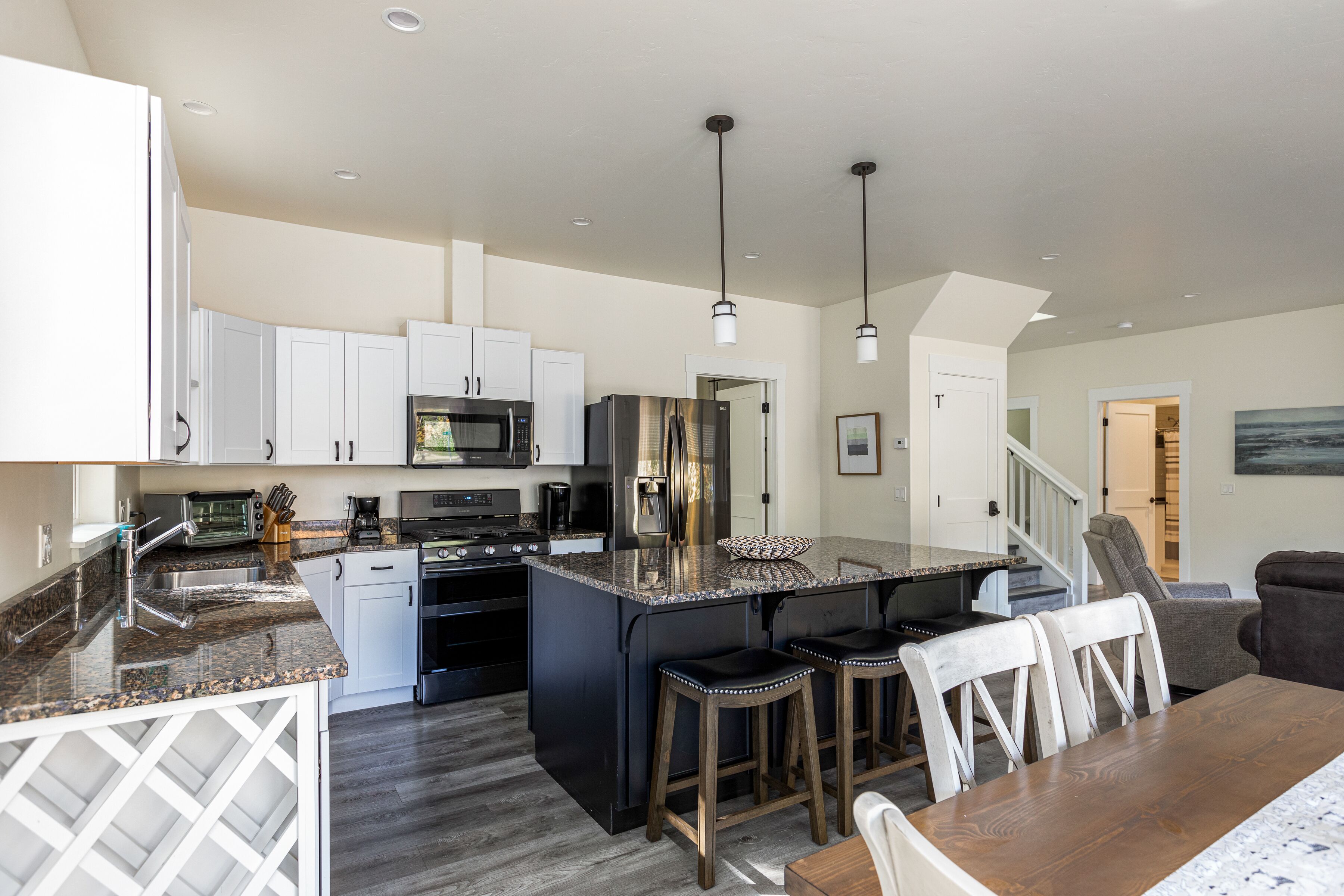 A modern kitchen with granite countertops, stainless steel appliances, and a central island with bar stools.