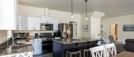 A modern kitchen with granite countertops, stainless steel appliances, and a central island with bar stools.