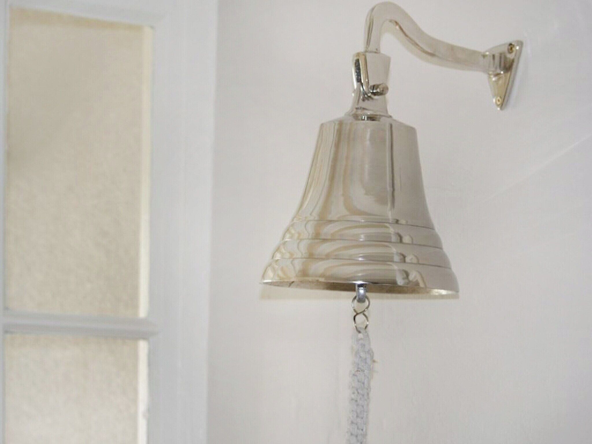 Una campana de vidrio transparente fijada a la pared, con una cadena colgando debajo.
