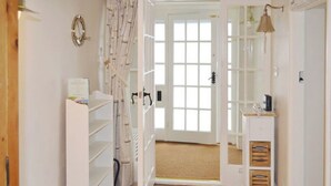A hallway with a wooden door, a white shelf unit, and a small desk with a lamp.