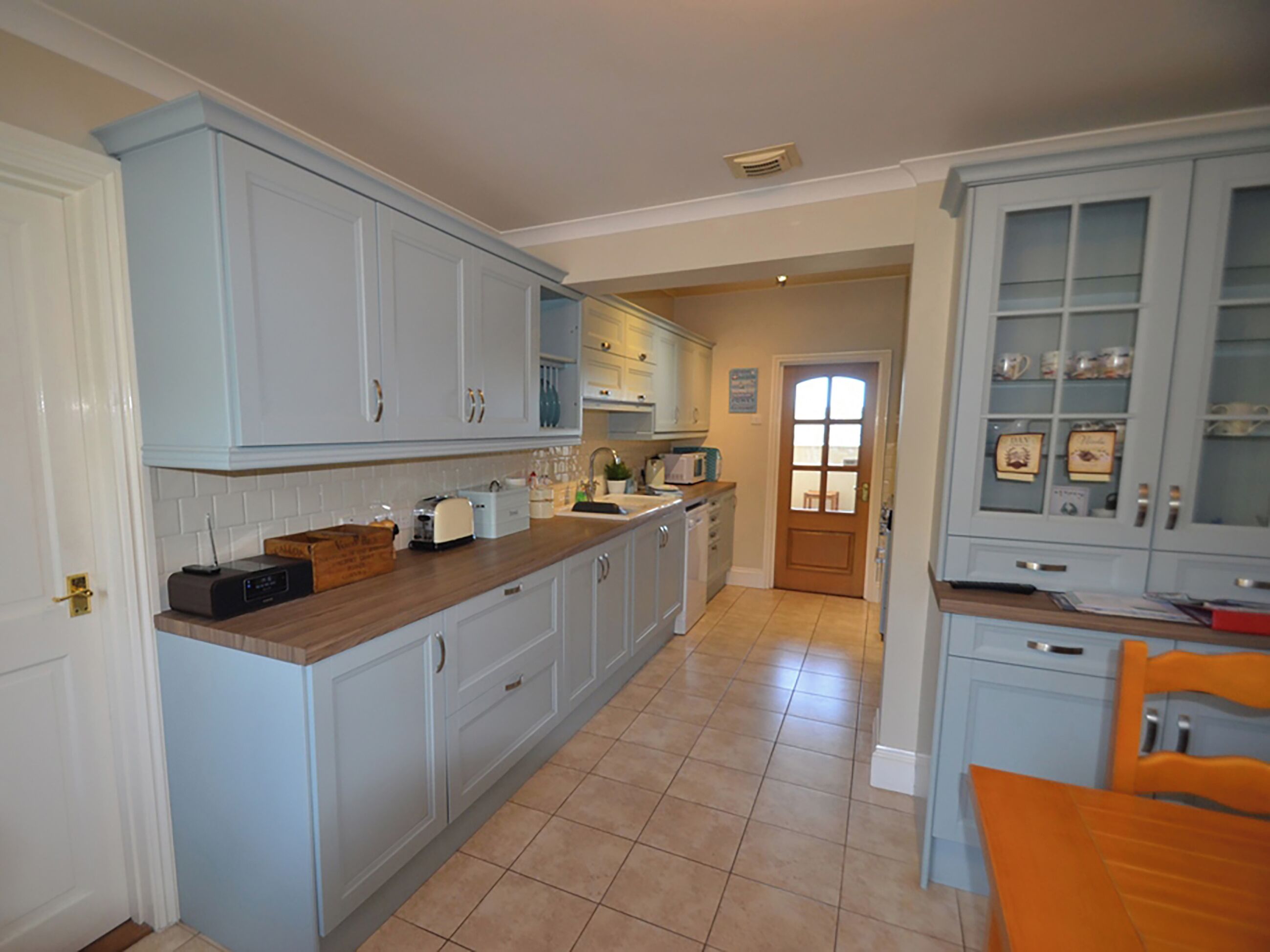 A kitchen with light blue cabinets, a wooden countertop, and a tiled floor.