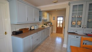 Cucina con pensili azzurri, un piano di lavoro in legno e pavimento piastrellato.
